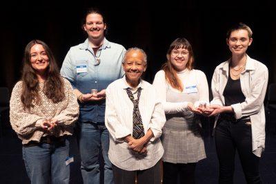 Nikki Giovanni stands in front of 10 students on stage at the poetry prize 
